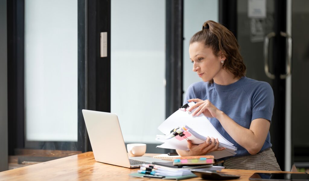 Business woman holding accounting bookkeeping documents checking financial data report