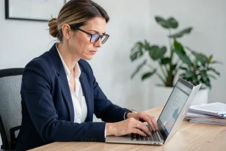 Femme professionnelle consultant un fichier de prévention sur un ordinateur portable dans un bureau moderne avec une expression concentrée